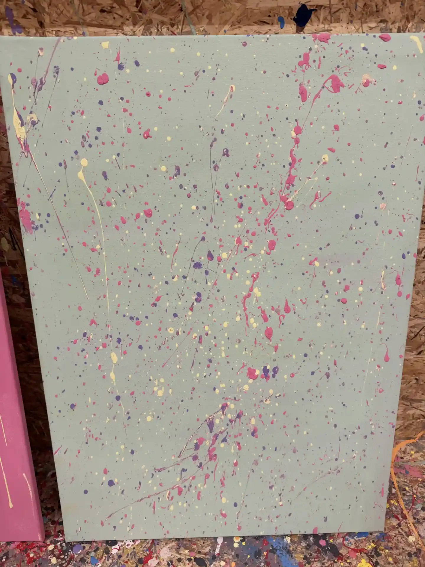 Leinwand in Salbeigrün mit feinen Spritzern in Pink, Violett und Creme – verspielt und leicht.