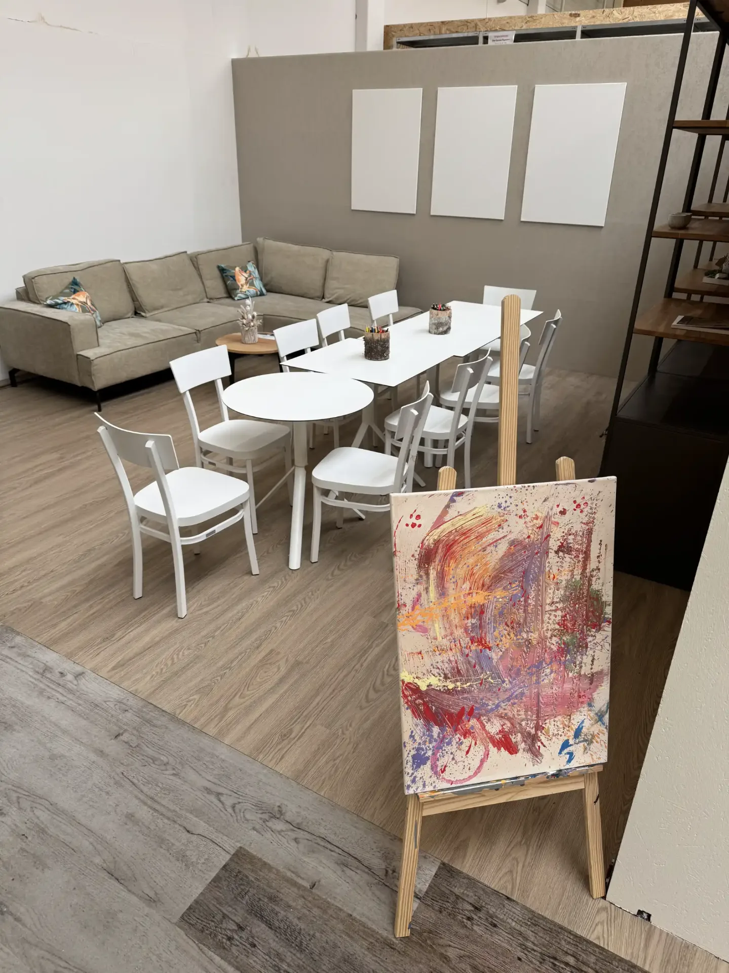 Blick in unser Actionpainting Studio mit Sitzecke, Maltisch und einem fertigen Kunstwerk auf der Staffelei.